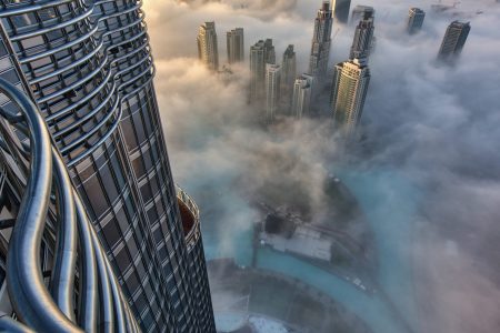 Aerial view of cityscape with skyscrapers above the clouds in Dubai, United Arab Emirates.